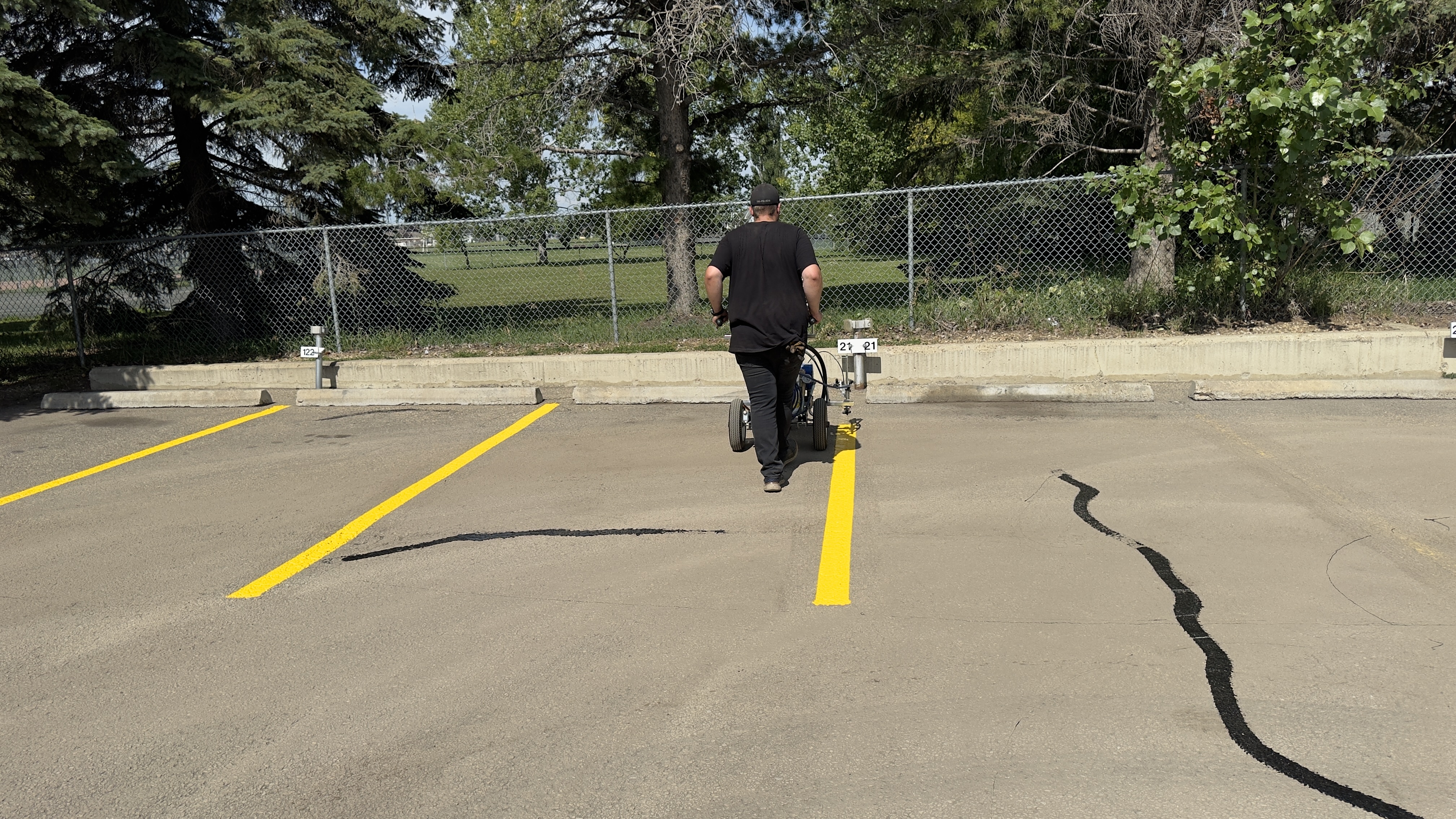 First Stop Contracting crew using laser-guided line painter on commercial lot